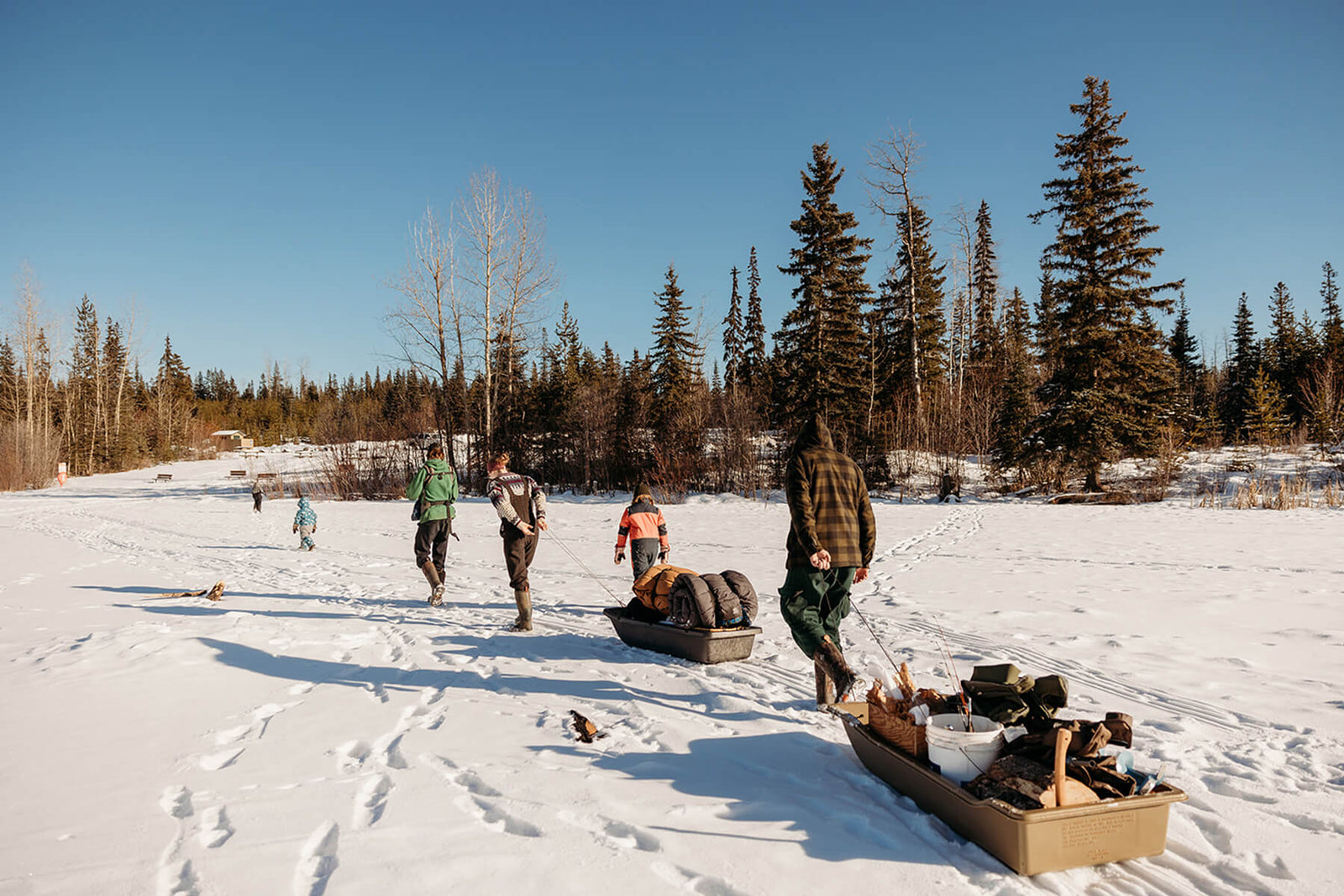 Kate Schat and family wearing Muck Boots wellingtons, pulling sledges loaded with supplies across a snow covered landscape