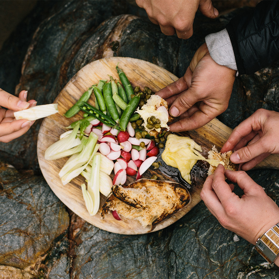 People sharing food on a wooden board