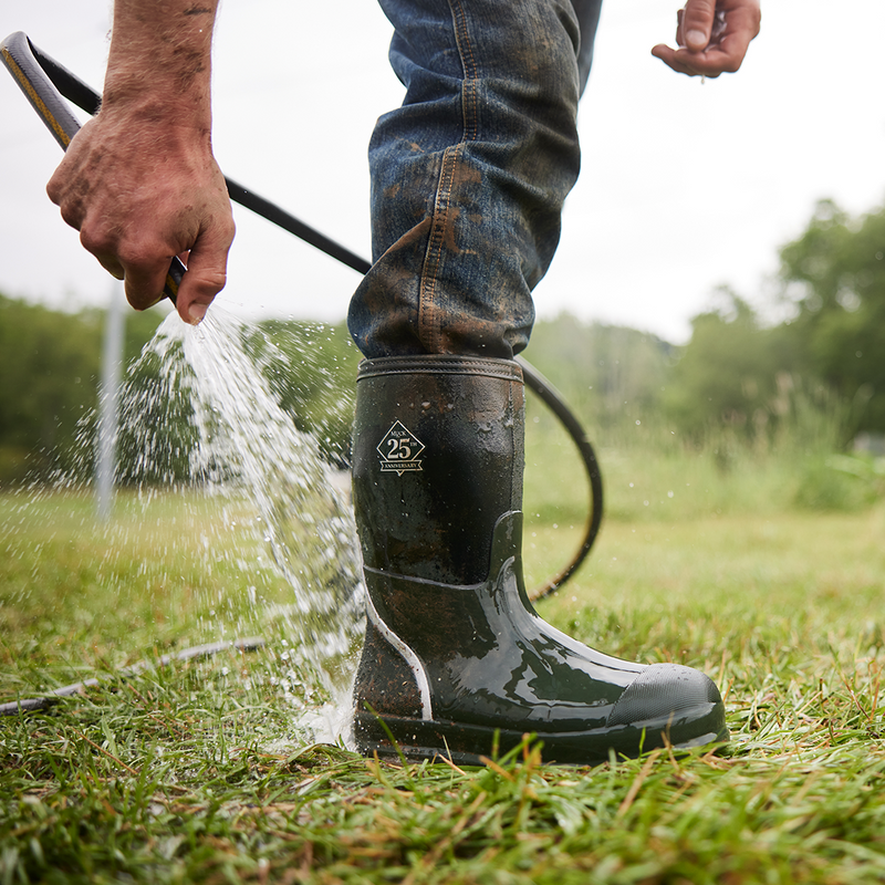 Close up image of a man washing a pair of Muck Boot Chore 25th Anniversary Wellingtons with a hose