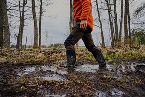 Man walking through muddy ground in a pair of Muck Boots