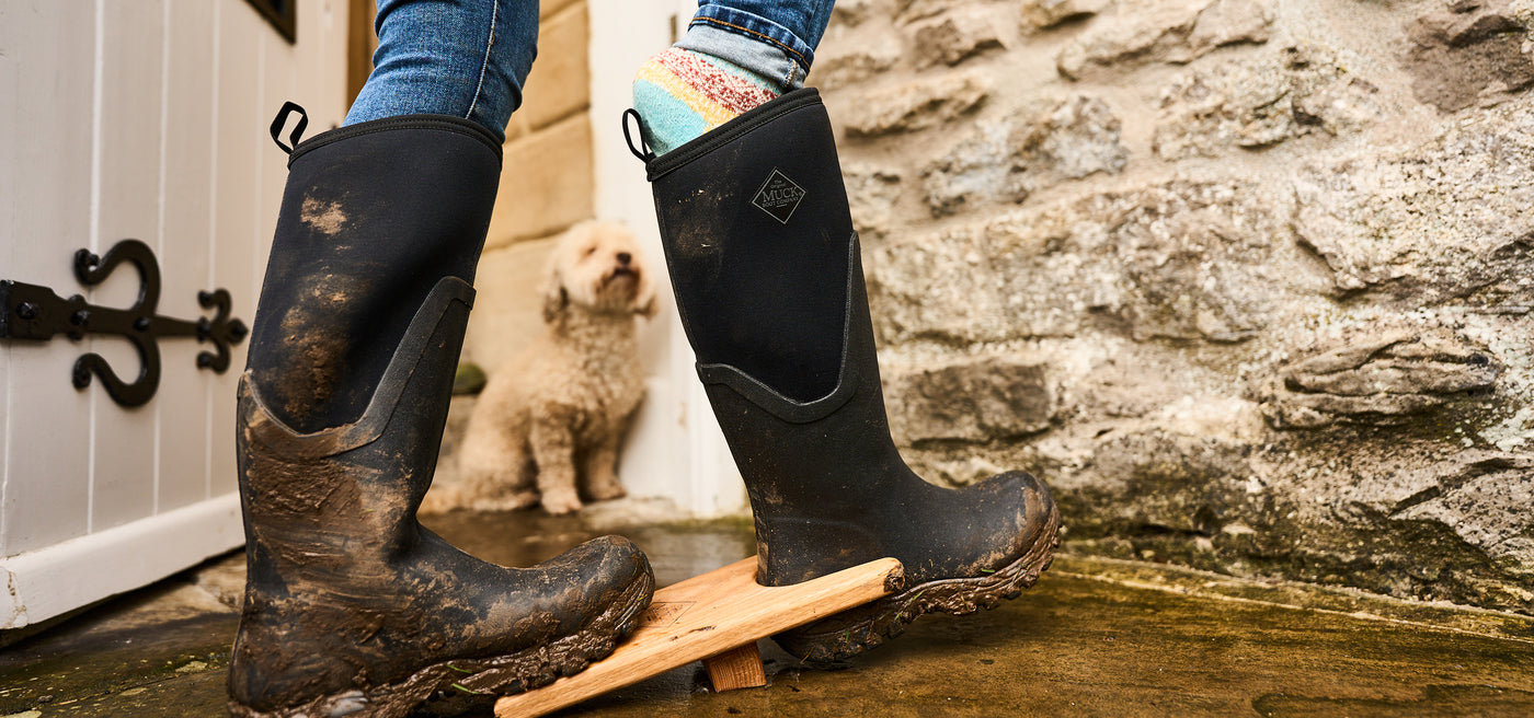 Person taking off a wellington boot with a boot jack