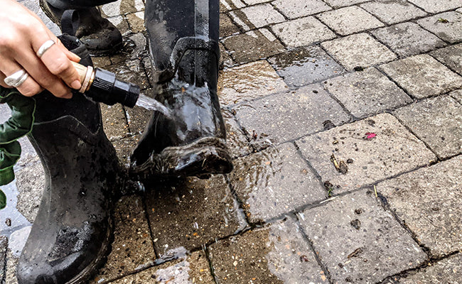 Person washing their boots with a hose
