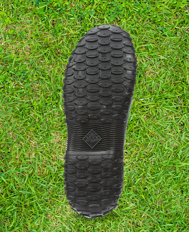 A Muck Boots Muckster outsole with a grass texture behind
