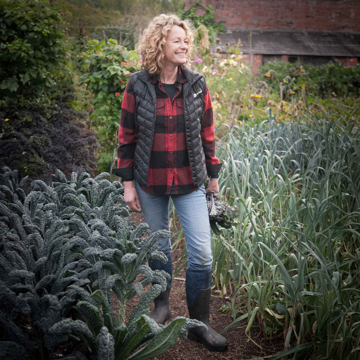 Kate Humble stood in the middle of a flower garden, wearing a pair of Muck Boots