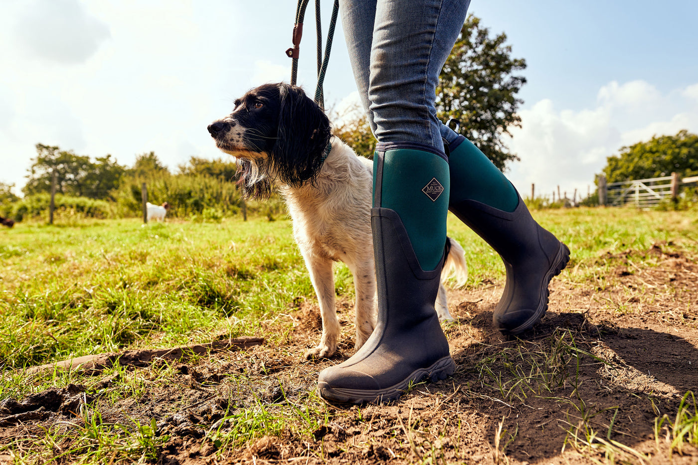 Person wearing a pair of Muck Boots Arctic Sport II Wellingtons, walking a dog in a field