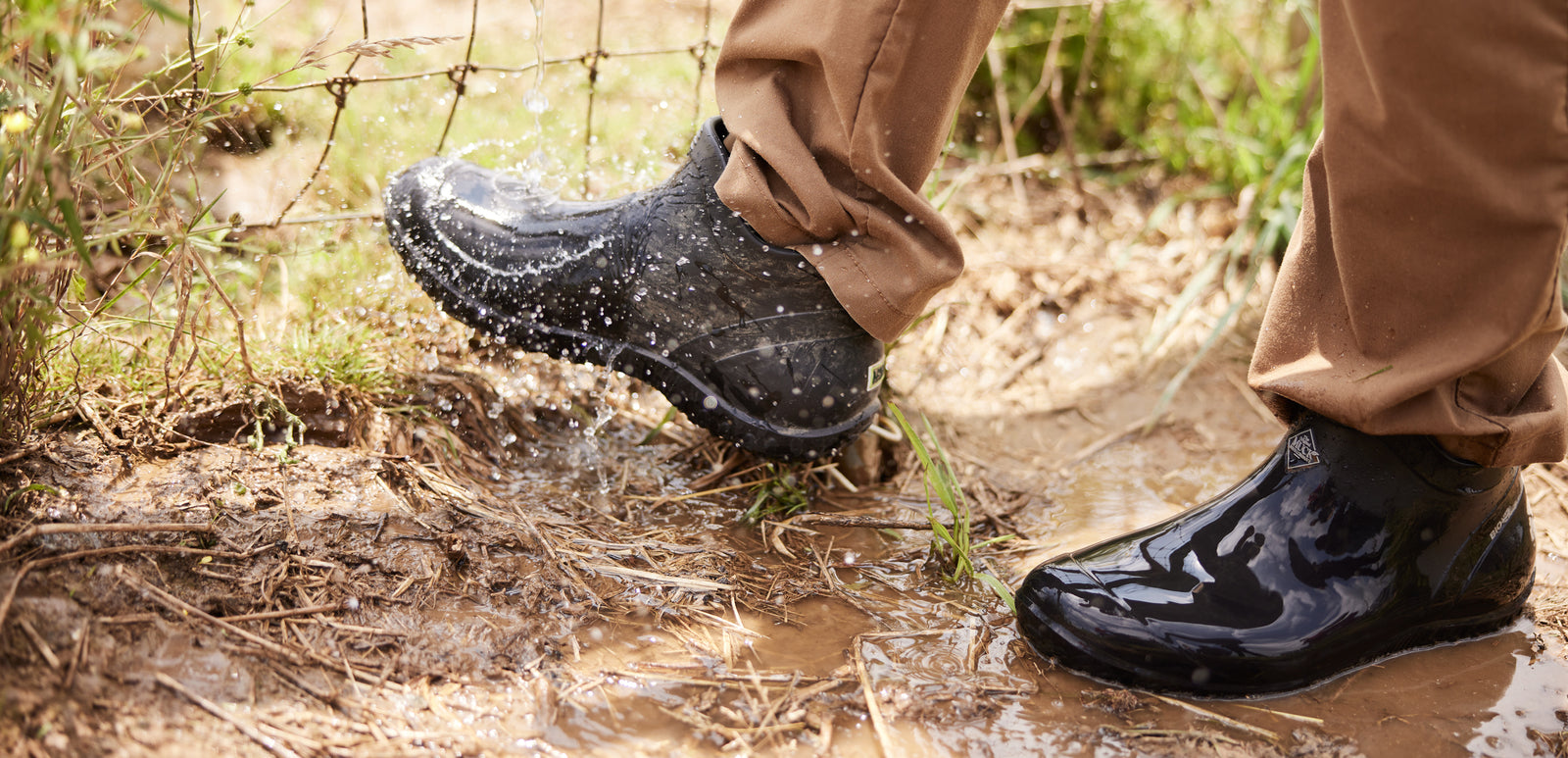 Person wearing a pair of black Muck Boot Muckster Lite Boots in a muddy puddle