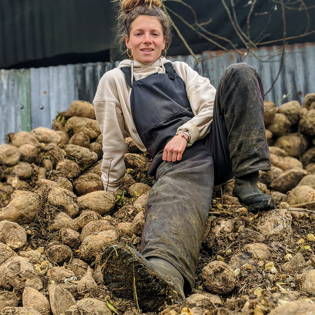 Woman sat on a pile of rocks wearing wellington boots