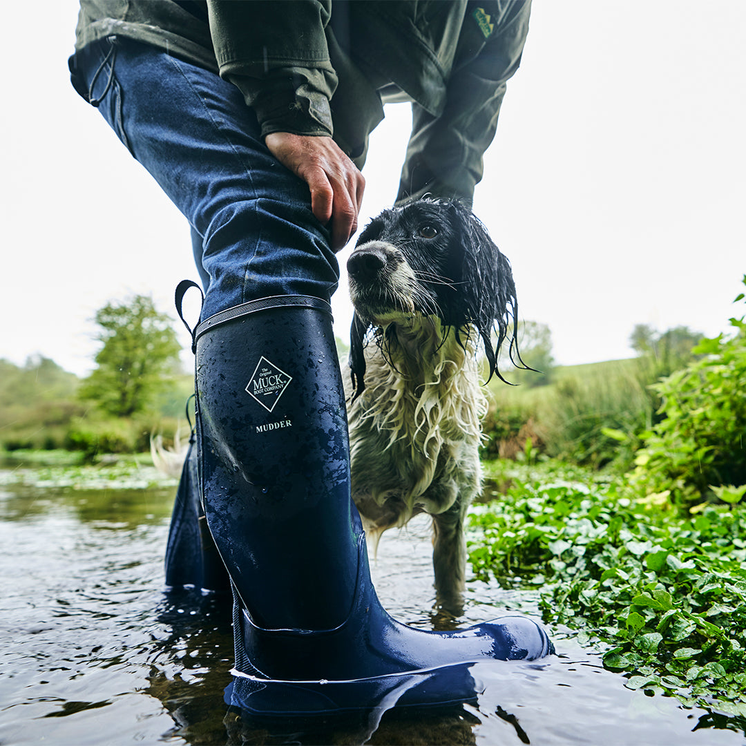 Person in wellies with dog in a river