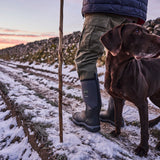 Person walking along a snowy path with their dog, wearing a pair of Muck Boots Unisex Calder Short Boots Black