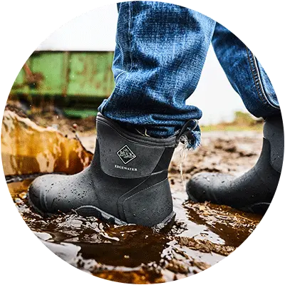 Person walking through a muddy puddle wearing a pair of Muck Boots Edgewater Boots.