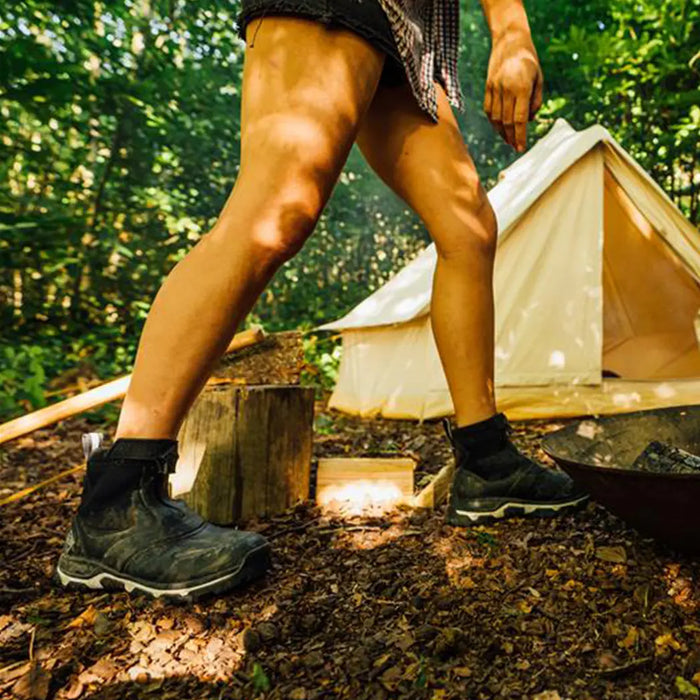 Close up image of a woman wearing a pair of Muck Boots Apex Zip Up Boots in a woodland campsite with tent behind.