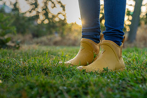 Close up image of a woman stood on grass wearing a pair of Muck Boot Muck Originals Pull-On Ankle Boots