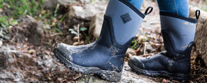 Person walking through mud, wearing a pair of Muck Boots Arctic Sport II short boots