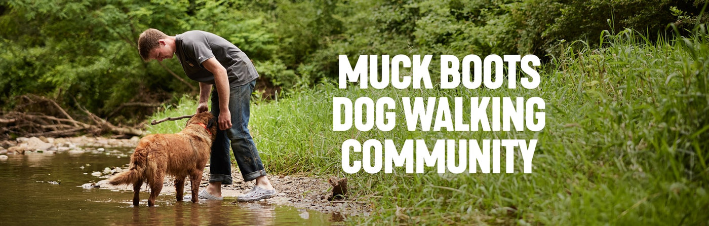 Boy wearing a pair of Muck Boots Muckster Clogs, playing with a dog in a stream. Text reads 'Muck Boot's Dog Walking Community'