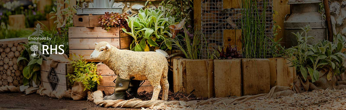 Muck Boots stand at the RHS logo and image of the Muck Boots Chelsea Flower show stand including a model sheep wearing a pair of Muck Boot wellingtons