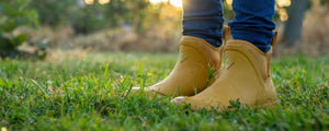 Close up image of a woman stood on grass wearing a pair of Muck Boot Muck Originals Pull-On Ankle Boots