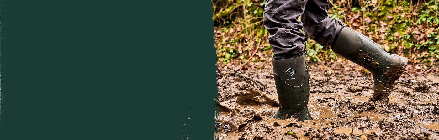 Person wearing a pair of green Muck Boots Rancher wellington boots walking through a muddy field