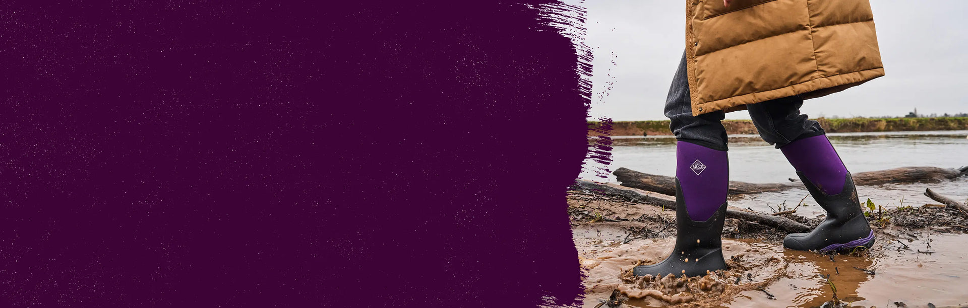 Person walking trough muddy water wearing a pair of Muck Boots Arctic Sport Wellingtons in Black Acai