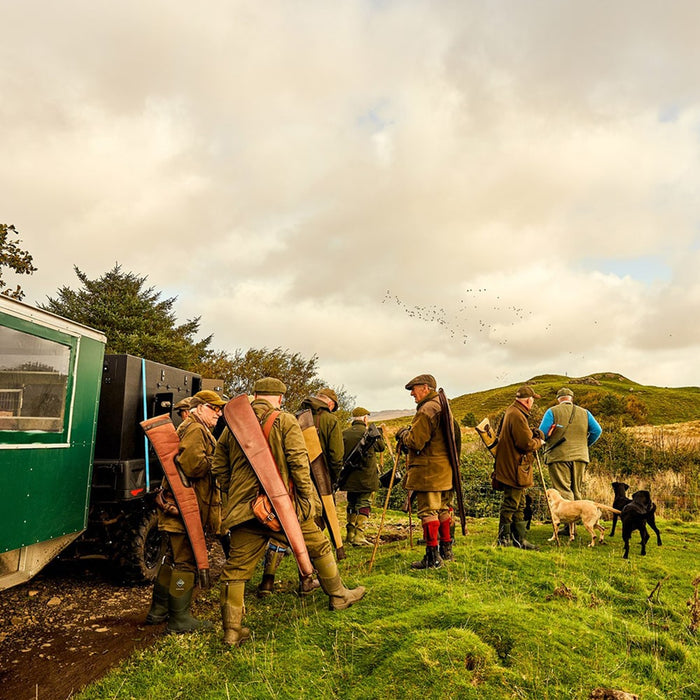 A group of men stood on a hill, wearing Muck Boots wellingtons, ready to go hunting