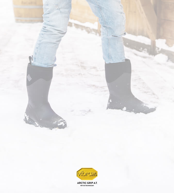 Person shovelling snow, wearing a pair of Muck Boots Arctic Ice Vibram wellingtons with a Vibram logo to the bottom of the image