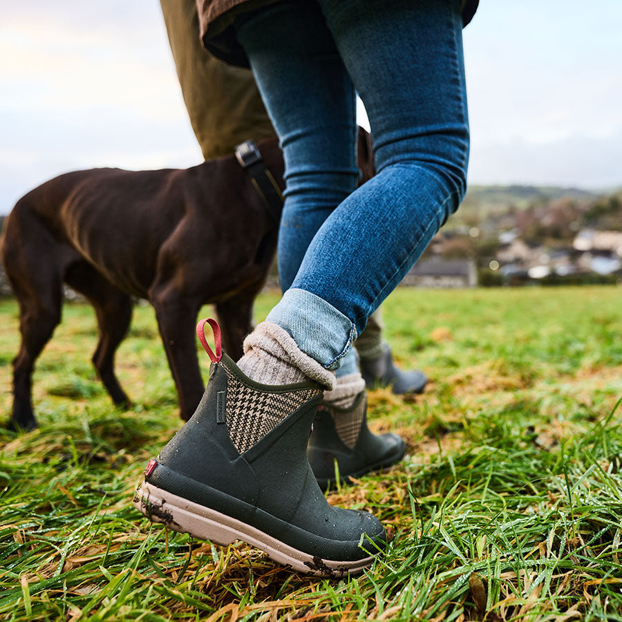 Close up of a woman walking her dog, wearing a pair of Muck Boot Muckster boots