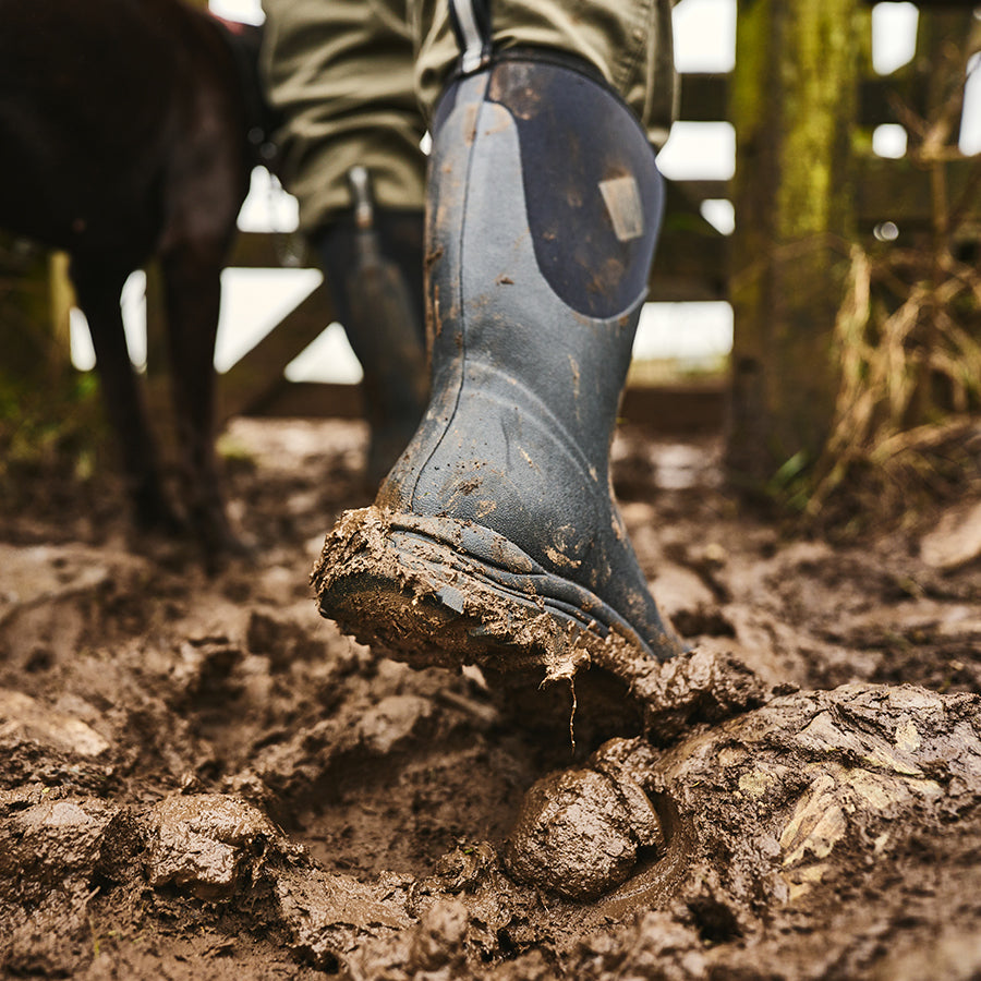 Person walking through mud wearing a pair of Muck Boots