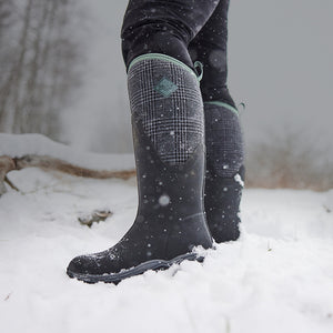 Person stood in snow, wearing a pair of Muck Boots