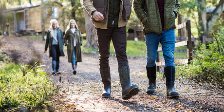 Two men walking along a path wearing Muck Boots wellingtons with two women out of focus following behind