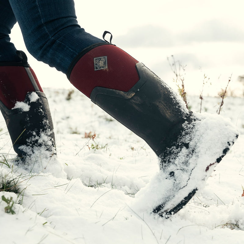 Close-up image of a woman wearing a pair of Muck Boots Arctic Ice wellingtons in the snow