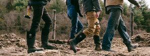 Four people walking along a rubble path, wearing cold weather clothing and Muck Boot wellingtons 